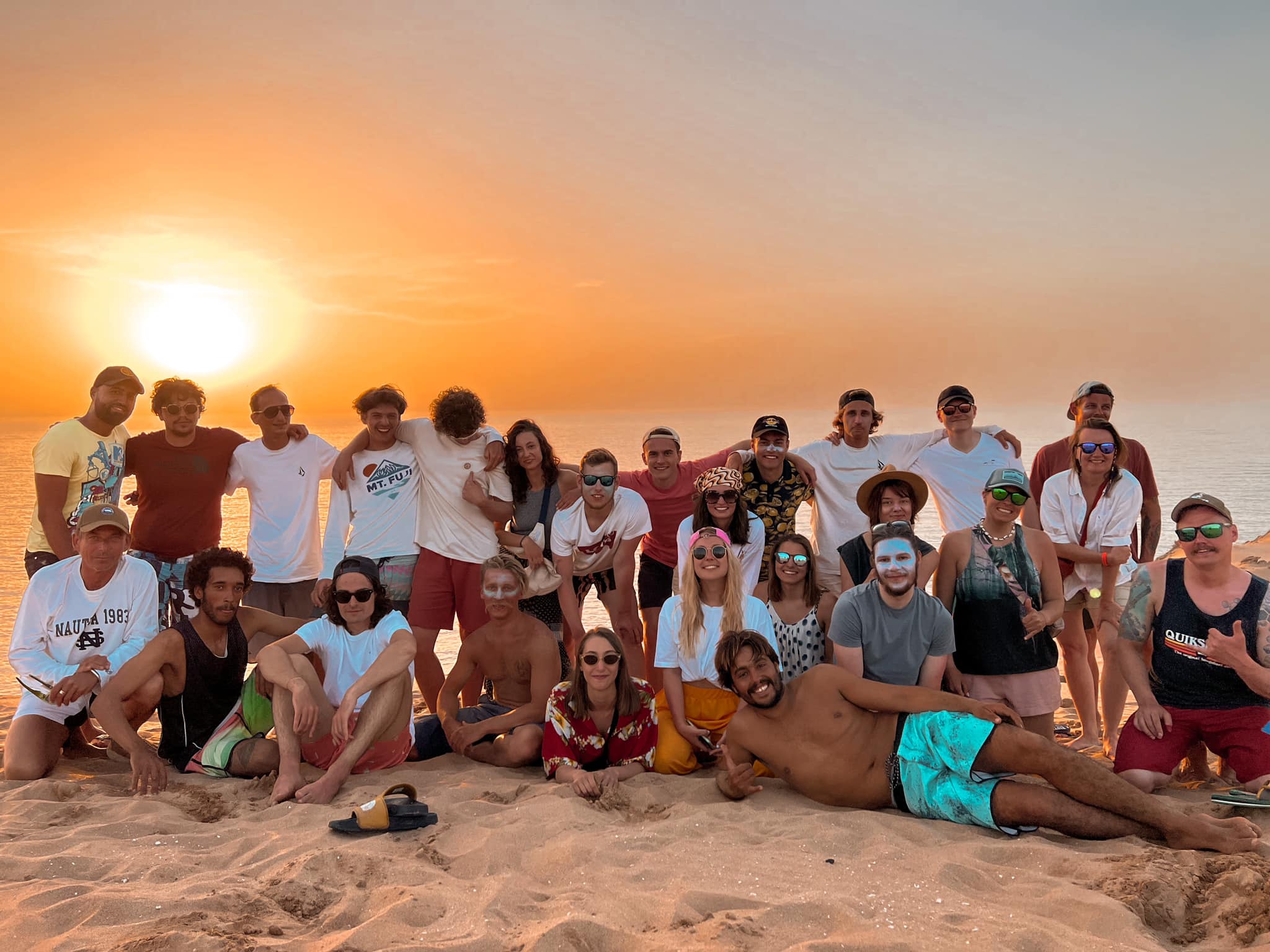 Voyageurs et moniteurs du camp réunis sur la plage au coucher du soleil