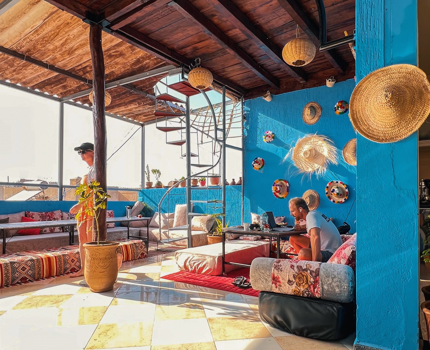 Terrasse rooftop couverte du riad avec banquettes berbères et mur bleu marocain