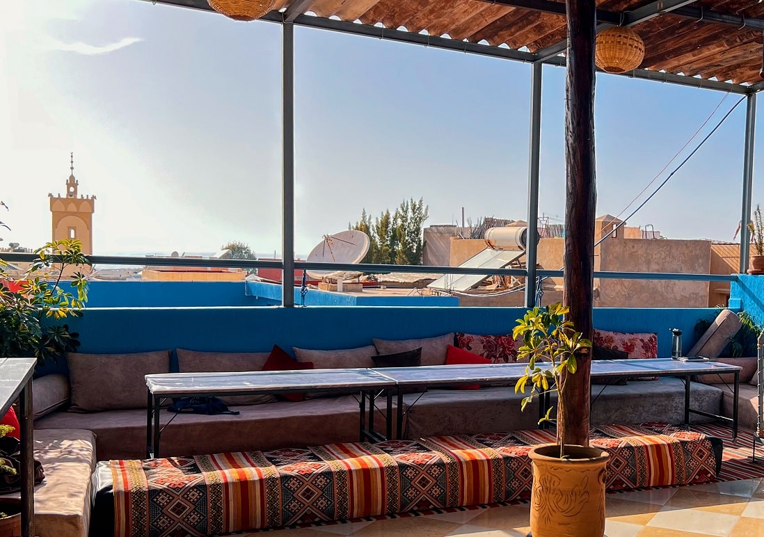 Terrasse rooftop couverte avec longues banquettes, dominant Tamraght
