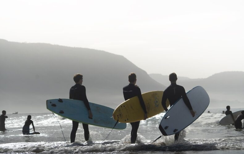 Surfeurs entrant dans l'Atlantique avec leurs planches au petit matin